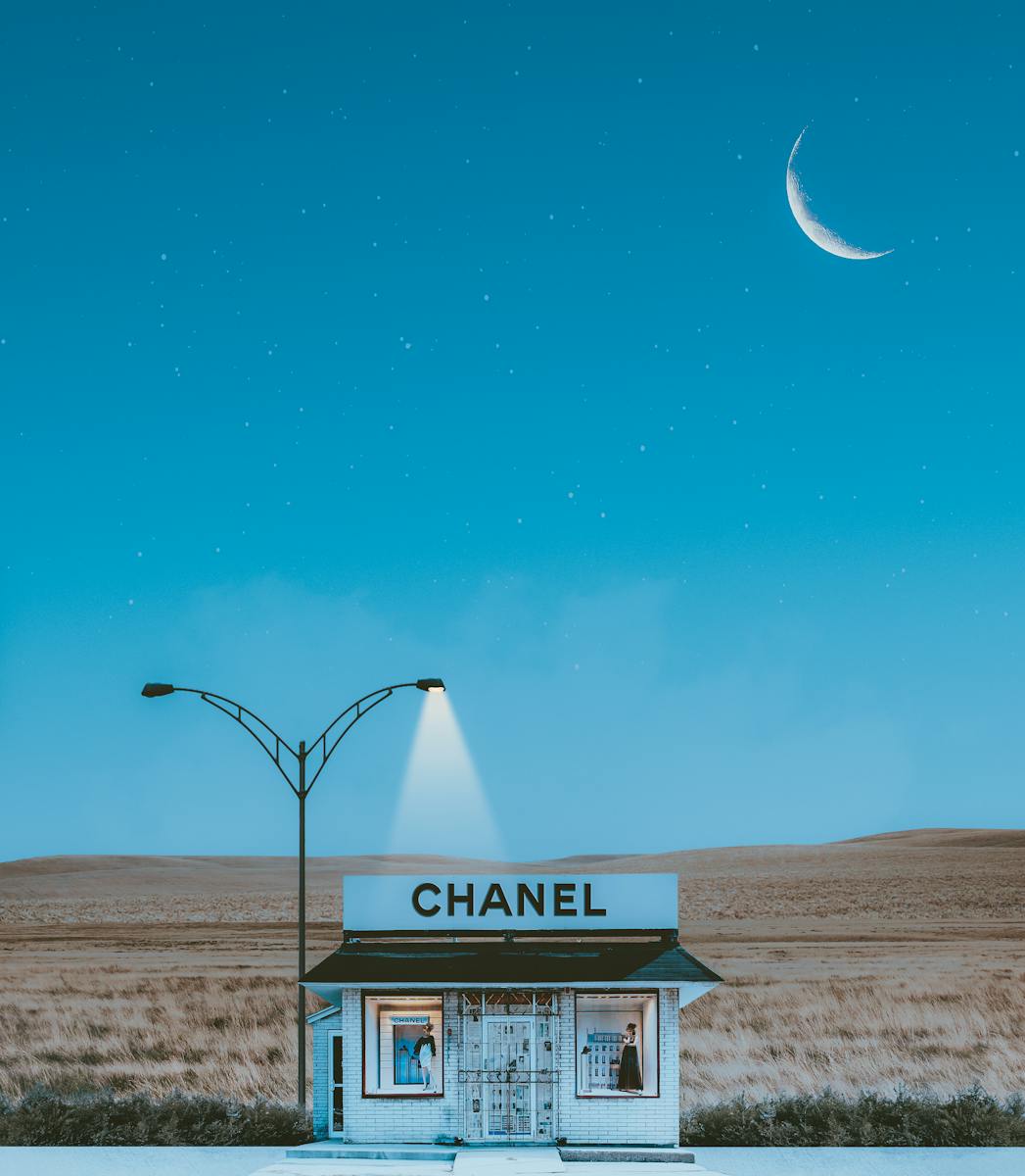 A minimalistic Chanel store illuminated by street lamps under a crescent moon and starry night sky.